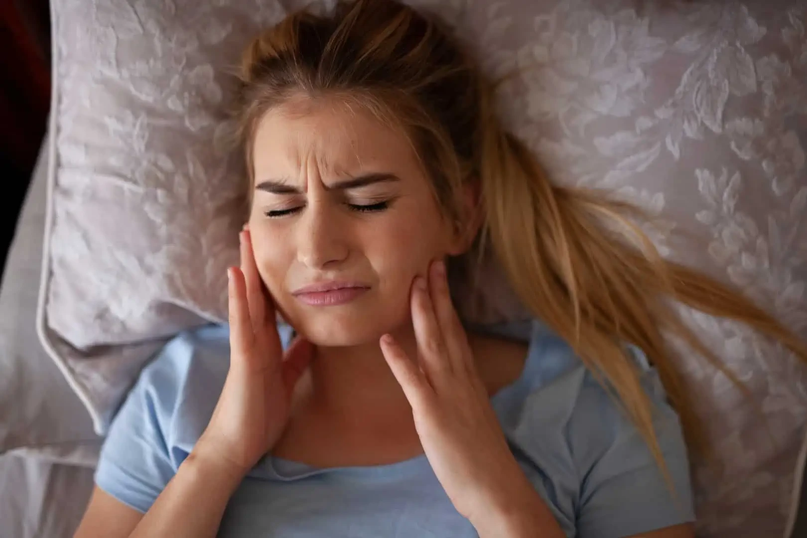 Woman holding jaw in discomfort
